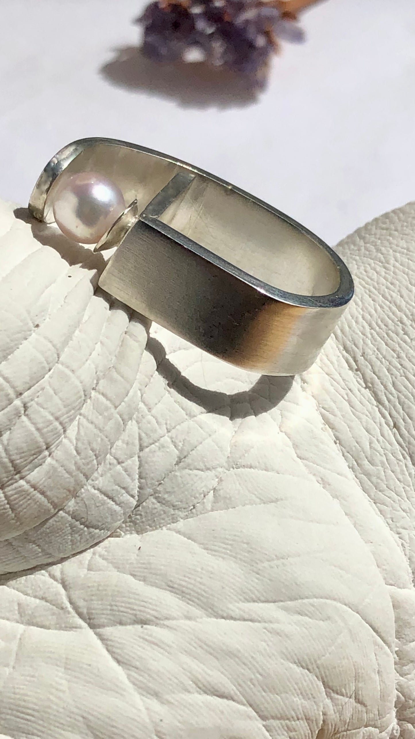 Silver ring with a pearl on a textured surface