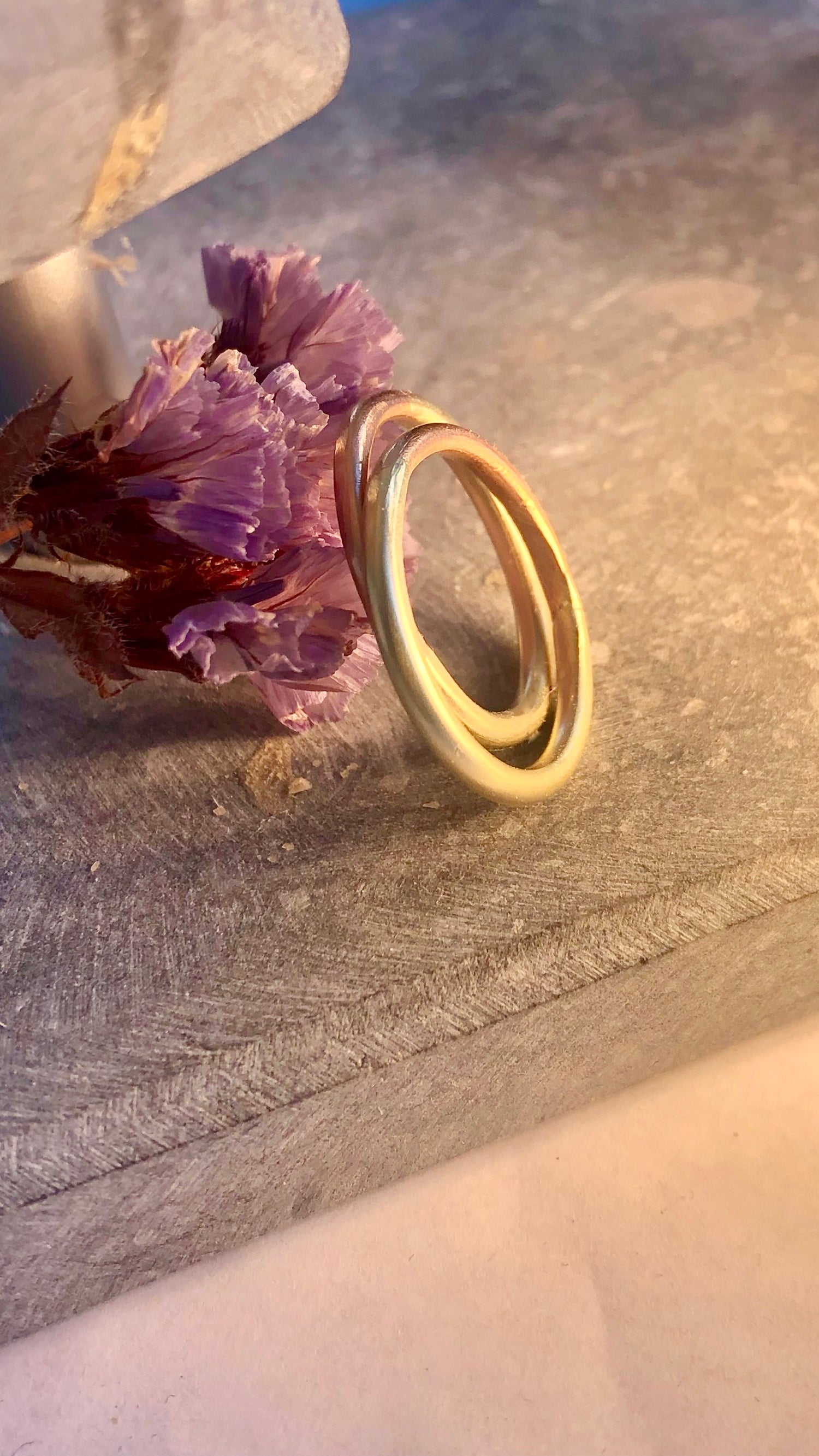 Gold ring on a textured surface with a purple flower romantic setting