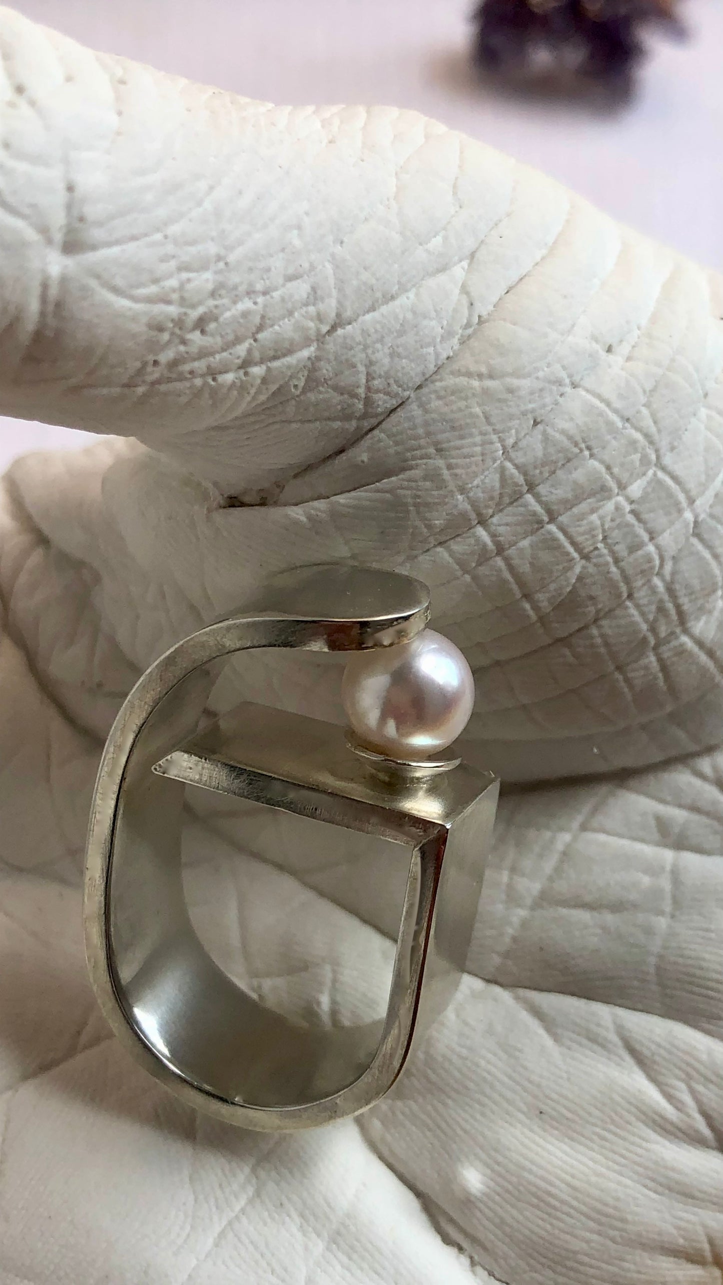 Silver ring with a pearl on a white surface