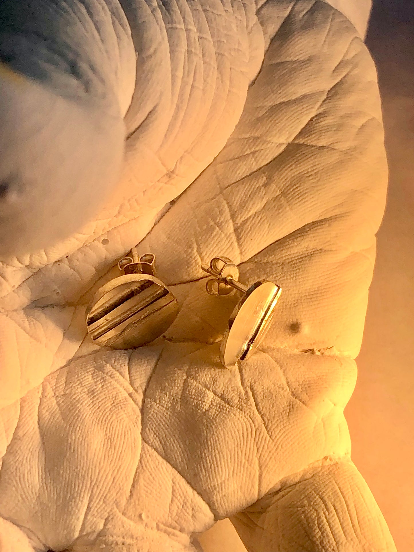 silver earrings on a textured surface of hand sculpture
