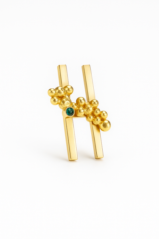 Gold brooch with green gemstone on a white background