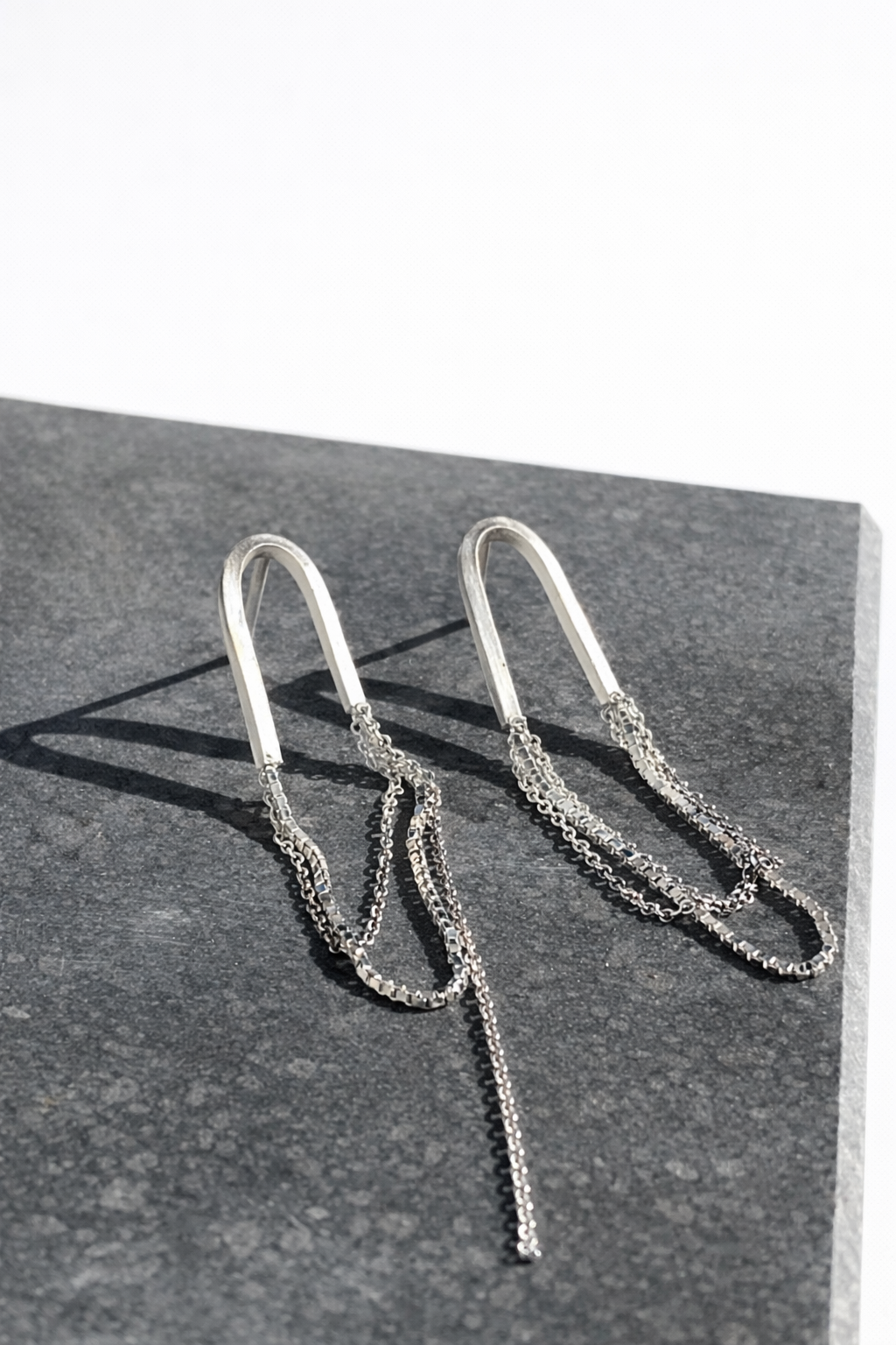Silver chain earrings on a dark surface