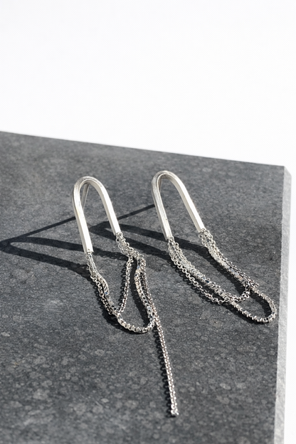 Silver chain earrings on a dark surface