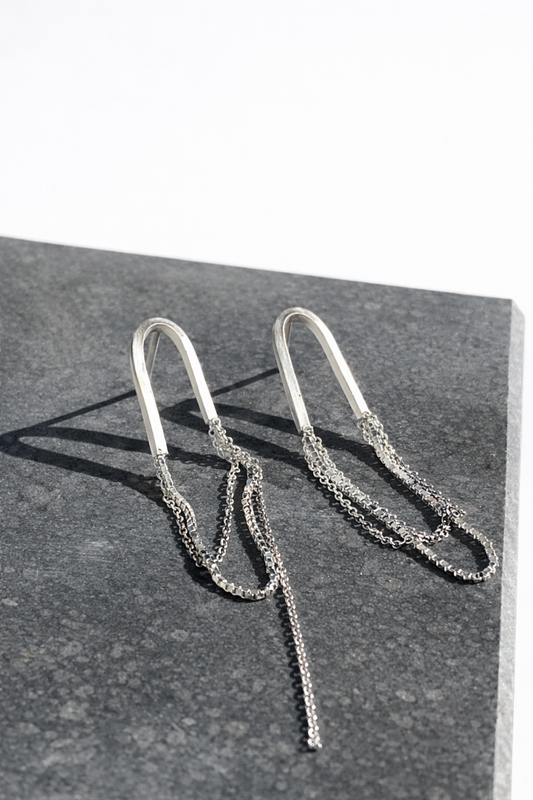 Silver chain earrings on a dark surface