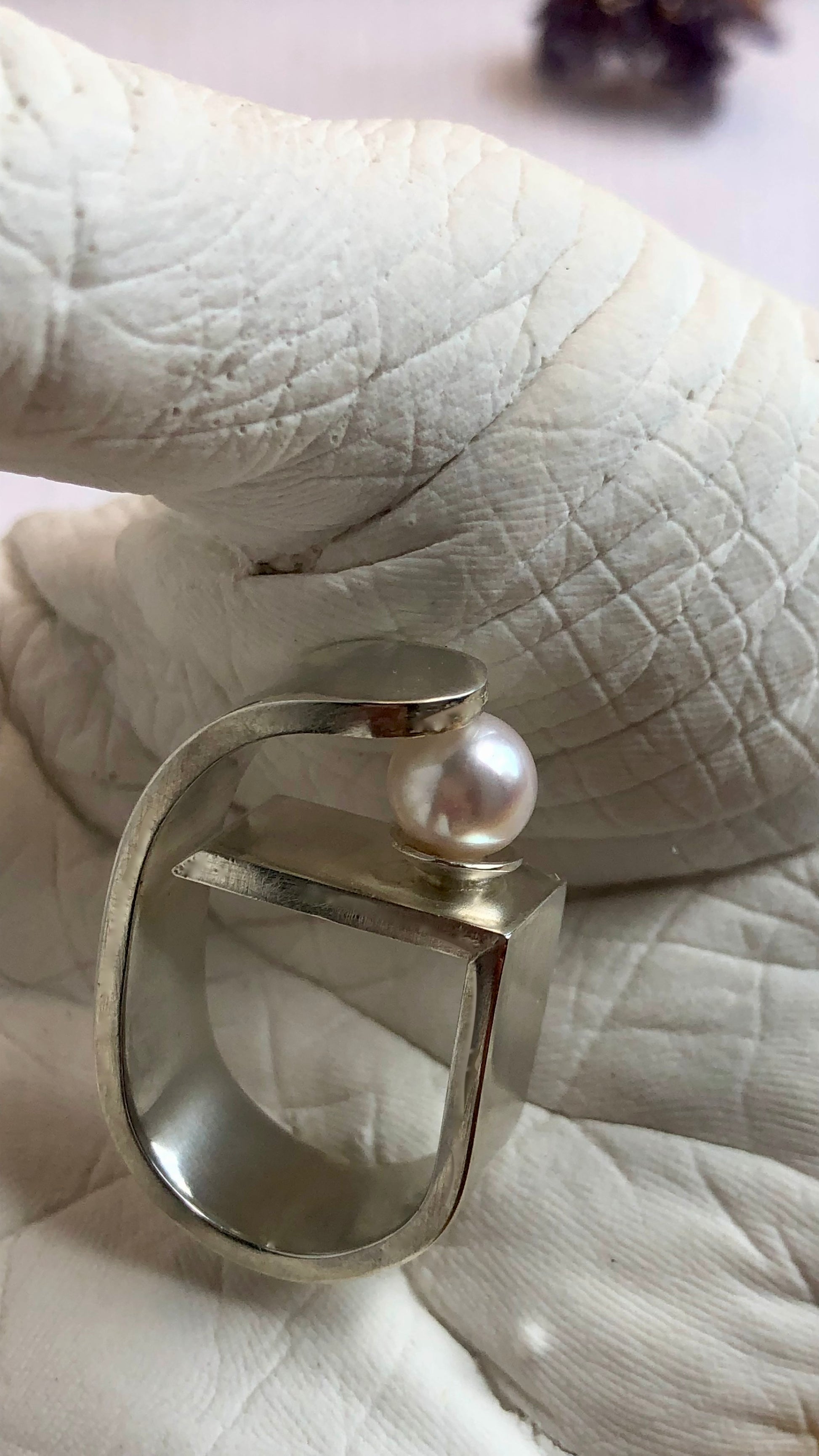 Silver ring with a pearl on a white surface