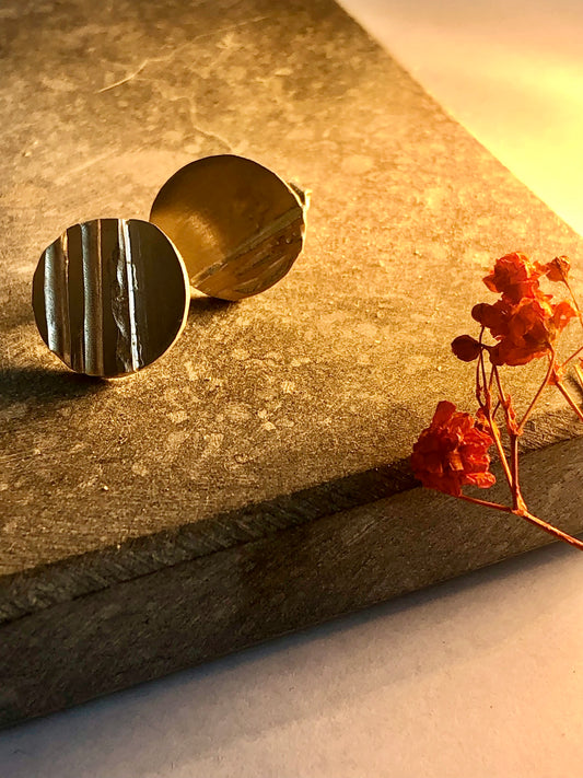 silver earstuds on a textured surface with dried flowers